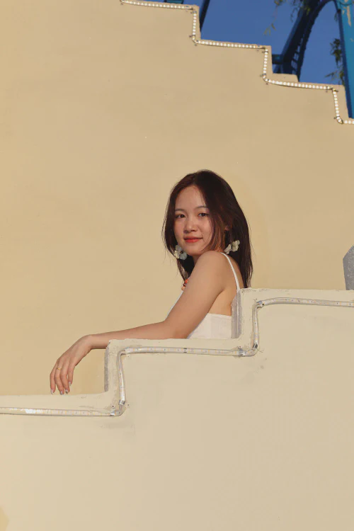 Yuting Peng sitting beside a warm yellow wall and steps.